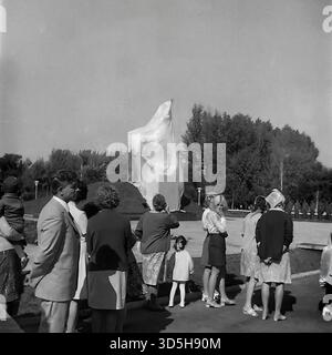 URSS, RSS d'Ukraine, Slavyansk, 1975. Un groupe de spectateurs, y compris des hommes, des femmes et un petit enfant, se rassemblent dans le parc Lénine (aujourd'hui parc Shekovichny). Ils regardent et attendent le dévoilement du nouveau Monument au soldat du libérateur, qui est vu dans le fond complètement recouvert d'un grand drap blanc. Un homme au premier plan tient un enfant dans ses bras. Cette photo d'archives en noir et blanc capture des citoyens ordinaires participant à la célébration du 30e jour de la victoire dans les années 1970 Banque D'Images