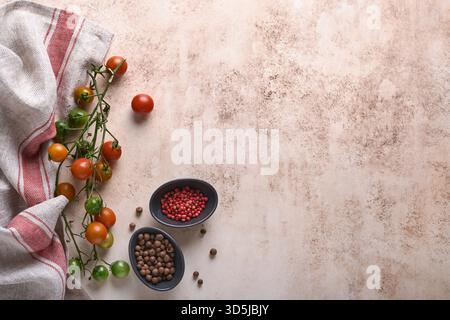 Branches de tomates cerises fraîches, serviette, poivre rouge et noir sur fond de marbre blanc. Fond de cuisine et maquette. Banque D'Images
