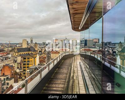 Belgique, Bruxelles, 31 décembre 2024 ; passerelle en bois d'un bâtiment moderne à façade vitrée offrant une vue panoramique imprenable sur le paysage urbain Banque D'Images