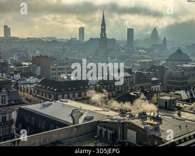 Belgique, Bruxelles, le 31 décembre 2024 ; de la fumée s'élève des toits à bruxelles, belgique, créant un paysage urbain brumeux par une journée brumeuse Banque D'Images