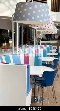 Intérieur de café moderne vide avec sièges colorés et abat-jour à pois à la lumière naturelle. Photo mobile Banque D'Images