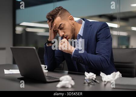 Homme d'affaires du moyen-Orient tousse au bureau tout en traitant avec la maladie pendant la pandémie Banque D'Images
