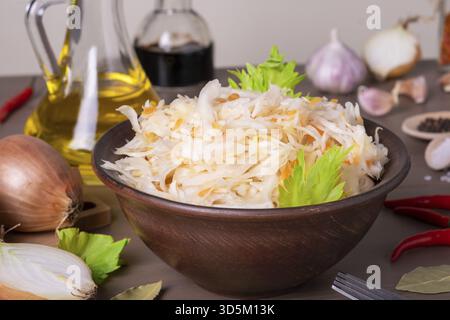 Gros plan du chou fermenté de choucroute dans un bol en céramique de choucroute sur table avec épices et ingrédients.Une alimentation saine et saine.Cuisine russe.Sélection Banque D'Images