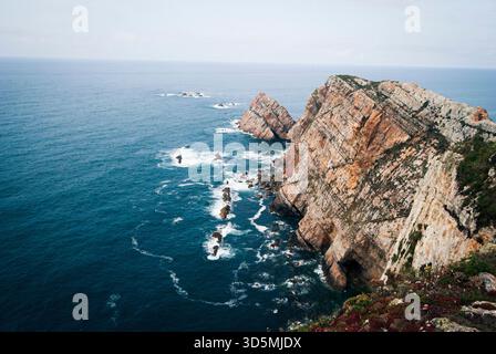 Des falaises verticales spectaculaires tombent dans l'Atlantique à Cabo de Peñas, où les vagues s'écrasent contre des formations rocheuses accidentées. Banque D'Images
