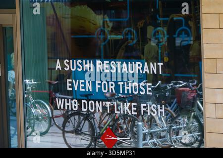 Vitrine du restaurant à Copenhague affichant le slogan humoristique sushi avec des vélos reflétés dans le verre. Banque D'Images