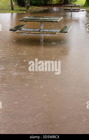 Parc public inondant vertical.Un terrain de pique-nique inondé et des tables après de fortes pluies. Banque D'Images
