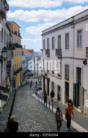Lisbonne, Portugal - 15 mai 2025 : les piétons flânent le long de la rue pavée devant les maisons colorées Banque D'Images