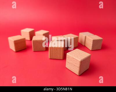 L'image montre plusieurs cubes de bois naturel non finis sur une surface rouge. Banque D'Images