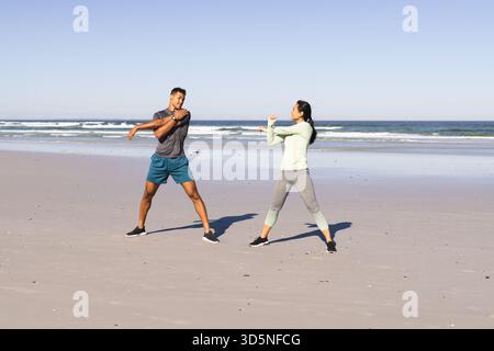 Couple s'exerçant sur la plage, s'étirant et s'échauffant pour l'entraînement du matin Banque D'Images