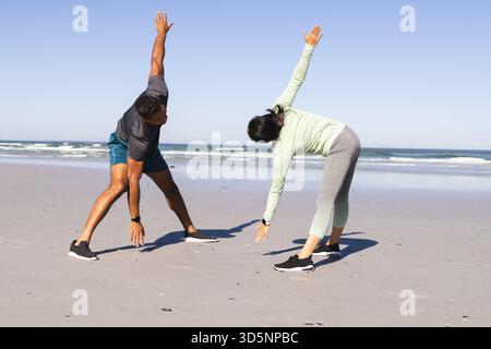 Couple s'exerçant sur la plage, s'étirant et profitant de l'entraînement en plein air ensemble Banque D'Images