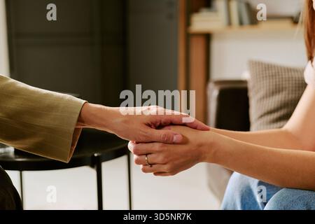 Femme caucasienne d'âge moyen tenant la main de jeune femme caucasienne réconfortante Banque D'Images