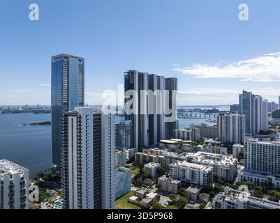 Vue aérienne de gratte-ciel imposants perçant le ciel bleu clair, contrastant avec les eaux chatoyantes entourant Edgewater, Miami, États-Unis. Banque D'Images