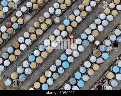 Vue aérienne d'innombrables conteneurs colorés alignés avec précision, créant des motifs géométriques, une personne en rouge marche au milieu d'eux, Ho Chi Minh ville, Ho Banque D'Images