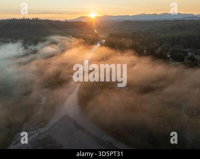 Vue aérienne du lever du soleil sur le sentier Foothills, avec de la brume couvrant doucement la rivière et les arbres, créant un paysage de rêve, Orting, Washington, Banque D'Images