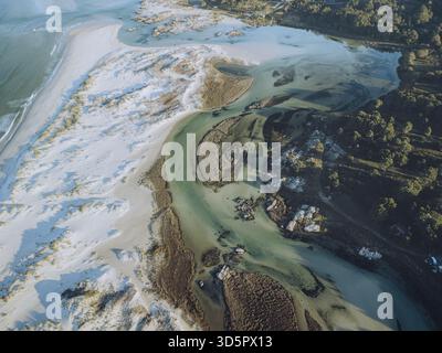 Vue aérienne de la rivière tranquille serpentant à travers l'étendue de sable, rencontrant le vaste océan, mettant en valeur l'art de la nature, Carnota, Une Corogne, Espagne Banque D'Images