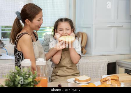 activités ensemble pendant les vacances. mère et fille prennent un repas ensemble pendant les vacances. femelle asiatique préparer le petit déjeuner le matin Banque D'Images