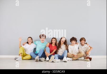 Des lycéens joyeux dans des vêtements colorés assis ensemble, embrassant et faisant des photos de groupe. Banque D'Images