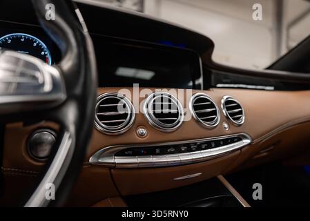 Tableau de bord de voiture de luxe rapproché avec ouïes chromées et horloge analogique Banque D'Images