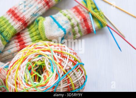 Fil de chaussette coloré affiché à côté des chaussettes tricotées, montrant des fibres vibrantes et une texture détaillée, idéal pour les thèmes liés aux projets de tricot, handma Banque D'Images