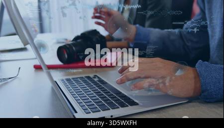 Taper les mains féminines portant un pull bleu à l'aide d'un ordinateur portable à la table avec DSLR et superpositions de données Banque D'Images