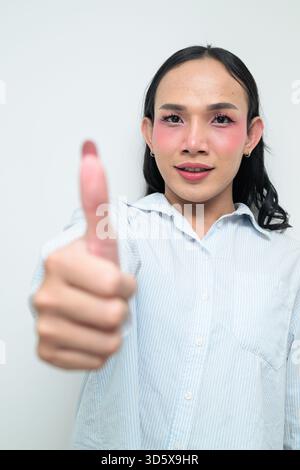 Portrait studio d'un jeune transgenre thaïlandais avec maquillage et cheveux longs. Concept d'expression de genre, fierté LGBTQ et inclusivité montrant un Banque D'Images