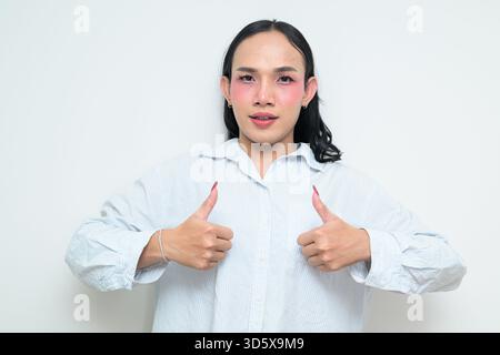Portrait studio d'un jeune transgenre thaïlandais avec maquillage et cheveux longs. Concept d'expression de genre, fierté LGBTQ et inclusivité montrant un Banque D'Images