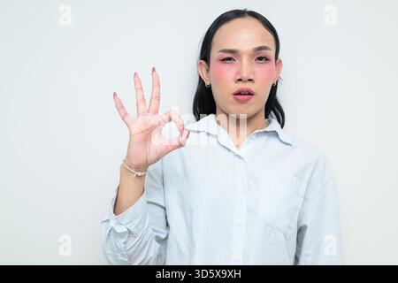 Portrait studio d'un jeune transgenre thaïlandais avec maquillage et cheveux longs. Concept d'expression de genre, fierté LGBTQ et inclusivité montrant un Banque D'Images