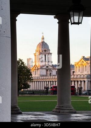 Londres, Royaume-Uni - 22 septembre 2025 : un grand bâtiment en dôme Old Royal Naval College encadré par des colonnes, avec une pelouse verte et un bus à impériale rouge à proximité Banque D'Images