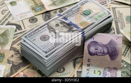 Pile de billets de cent dollars américains superposés avec un billet chinois de cinq yuans Banque D'Images