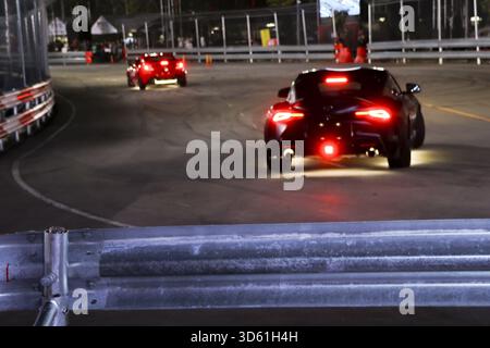 Course nocturne palpitante sur circuit sombre avec voiture de sport rapide. le feu arrière rouge lumineux illumine la piste asphaltée pendant les compétitions intenses et les sports mécaniques Banque D'Images