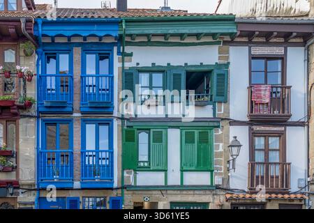 Bâtiments traditionnels colorés, balcons fermés bleu vert brun, façades blanches, volets en bois, architecture historique, style basque Banque D'Images