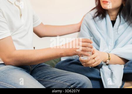 Plan recadré de femme avec problème de santé à la maison et mari prenant soin de femme pendant les maladies. Gros plan, mise au point sélective. Banque D'Images