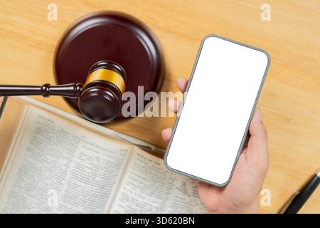 Main tenant un téléphone avec écran isolé avec un marteau en bois et livre sur la table d'une vue de dessus. Copier l'espace. Banque D'Images
