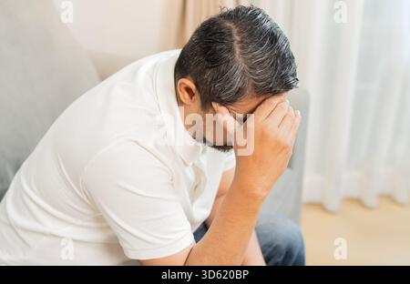 Vue en angle élevé de l'homme mûr assis à la maison, près d'une porte, avec la main dans la tête. Concept de stress et de céphalées. Banque D'Images
