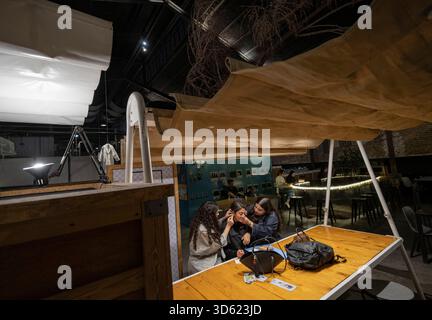 Téhéran, Iran. 17 novembre 2025. Deux jeunes iraniennes aident leur amie à porter ses boucles d’oreilles dans un centre de créativité et d’innovation à Téhéran, en Iran, le 17 novembre 2025. La semaine du design de Téhéran est un événement inclusif qui tisse le design dans le tissu de la vie urbaine, créant une plate-forme de dialogue créatif entre designers, producteurs et passionnés. (Photo de Morteza Nikoubazl/NurPhoto) crédit : NurPhoto SRL/Alamy Live News Banque D'Images