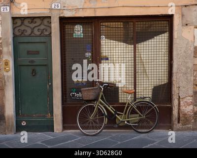 Une vieille femme vélo appuyé contre la fenêtre d'un vieux magasin vide à Lucca Toscane Italie Banque D'Images
