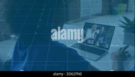 Regarder une femme en haut bleu penché vers un ordinateur portable au bureau, avec des présentateurs portant une veste blazer Banque D'Images