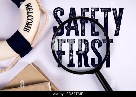 Loupe se concentrant sur la sécurité du texte d'abord avec le symbole de bouée de sauvetage représentant le concept de mise en garde et de protection du lieu de travail. Banque D'Images