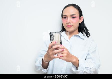 Portrait studio d'un jeune transgenre thaïlandais avec maquillage et cheveux longs. Concept d'expression de genre, fierté LGBTQ et inclusivité montrant un Banque D'Images