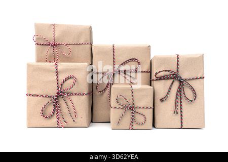 Concept de colis de Noël. boîtes cadeaux enveloppées dans du papier kraft brun attaché avec une ficelle rouge, blanche et verte en forme d'arc isolé sur fond blanc. Banque D'Images