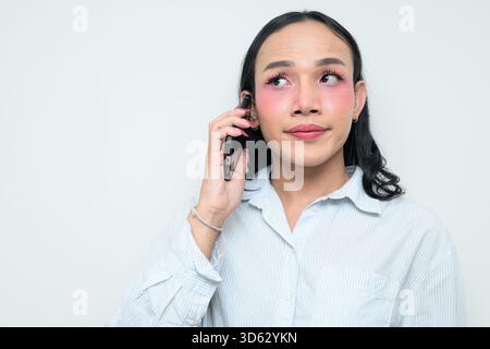 Portrait studio d'un jeune transgenre thaïlandais avec maquillage et cheveux longs. Concept d'expression de genre, fierté LGBTQ et inclusivité montrant un Banque D'Images