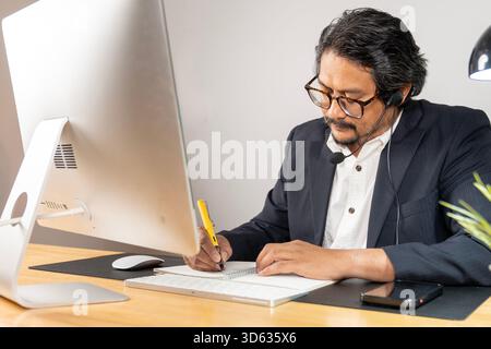 Le jeune employé de bureau est assis à l'ordinateur en travaillant avec son esprit à l'esprit Banque D'Images