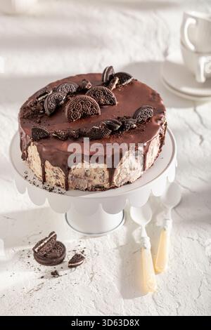 Cheesecake sucré servi sur une table en bois blanc. Biscuit au fromage avec glaçage au chocolat. Banque D'Images