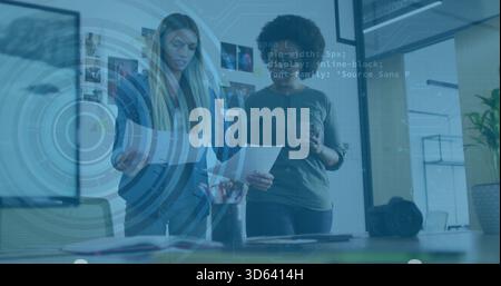 Examen de deux femmes en tenue d'affaires tenant gobelet en papier et des mises en page dans un bureau moderne, recouvrement AR Banque D'Images