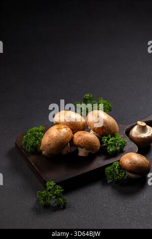 Champignons cremini frais et brins de persil vert vif disposés sur une planche à découper en bois rustique, prêts à cuisiner et à préparer de délicieux plats sains Banque D'Images