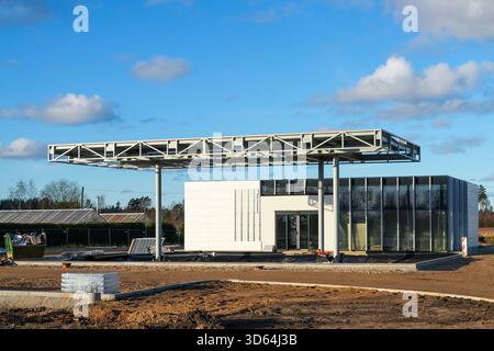 Une nouvelle station-service est en construction, avec une grande charpente en acier et un bâtiment de service moderne pendant que les ouvriers préparent le site Banque D'Images