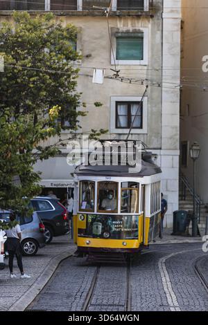 Lisbonne, Portugal - 18 juillet 2020 : vue sur l'emblématique tramway jaune qui glisse le long des pistes, niché entre des bâtiments anciens et des arbres verdoyants. Banque D'Images