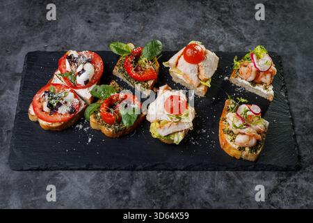Plat élégant de crostini en bouchées garni de tomates, fromage, basilic et fruits de mer. Idéal pour les fêtes, la restauration ou les divertissements élégants avec vibra Banque D'Images