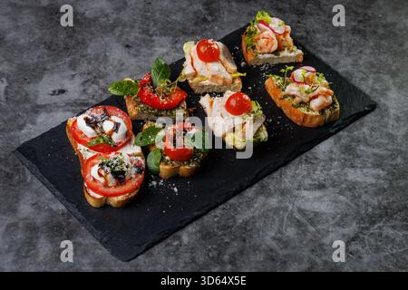 Plat élégant de crostini en bouchées garni de tomates, fromage, basilic et fruits de mer. Idéal pour les fêtes, la restauration ou les divertissements élégants avec vibra Banque D'Images