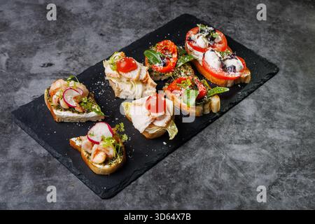 Plat élégant de crostini en bouchées garni de tomates, fromage, basilic et fruits de mer. Idéal pour les fêtes, la restauration ou les divertissements élégants avec vibra Banque D'Images